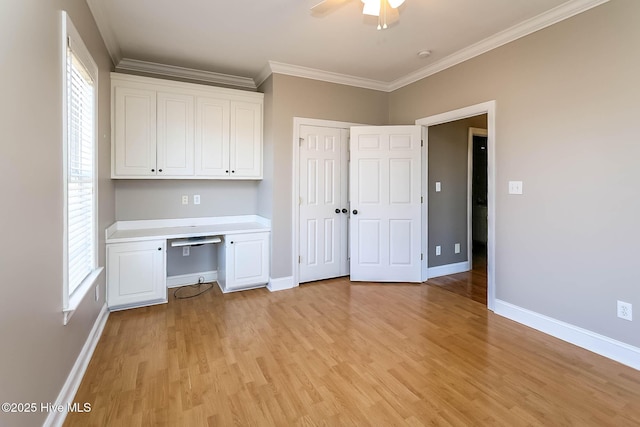 unfurnished office featuring ornamental molding, light wood-type flooring, built in study area, and baseboards