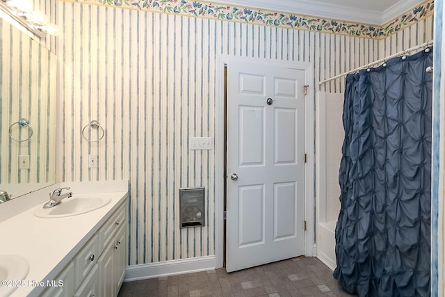 bathroom with a sink, baseboards, double vanity, shower / bath combo with shower curtain, and wallpapered walls