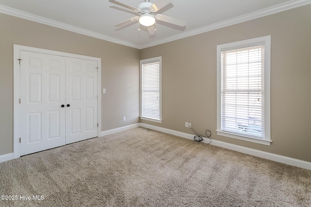 carpeted empty room featuring baseboards, a ceiling fan, and crown molding