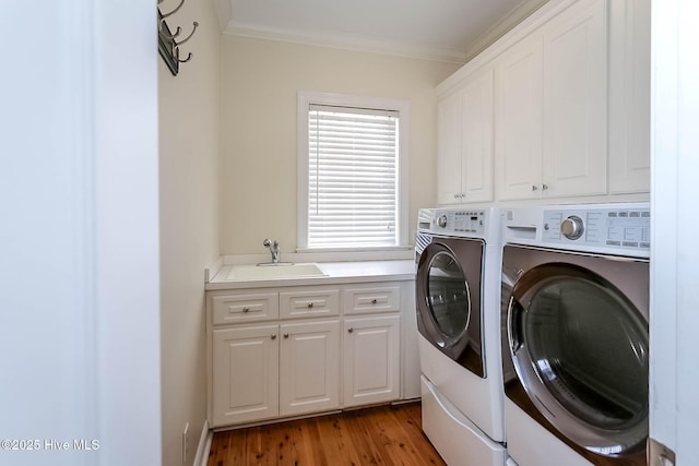 laundry area featuring crown molding, washing machine and dryer, cabinet space, and a sink