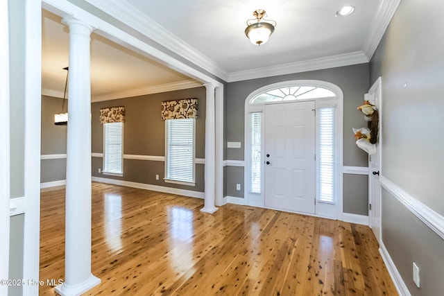 entrance foyer with crown molding, decorative columns, and wood finished floors