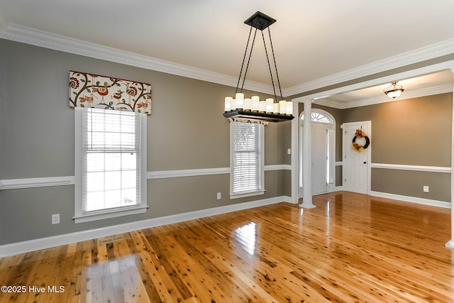 unfurnished dining area with ornate columns, ornamental molding, and hardwood / wood-style floors