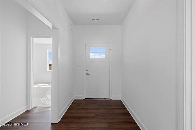 doorway with dark wood-style floors, visible vents, and baseboards