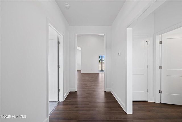 corridor featuring baseboards and dark wood-style flooring