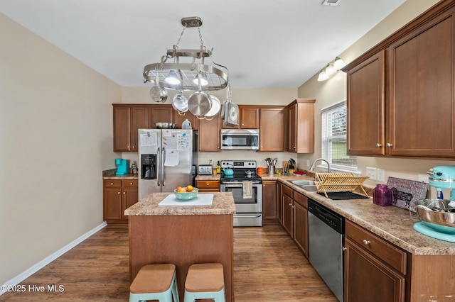 kitchen featuring a sink, a kitchen island, stainless steel appliances, and dark wood finished floors