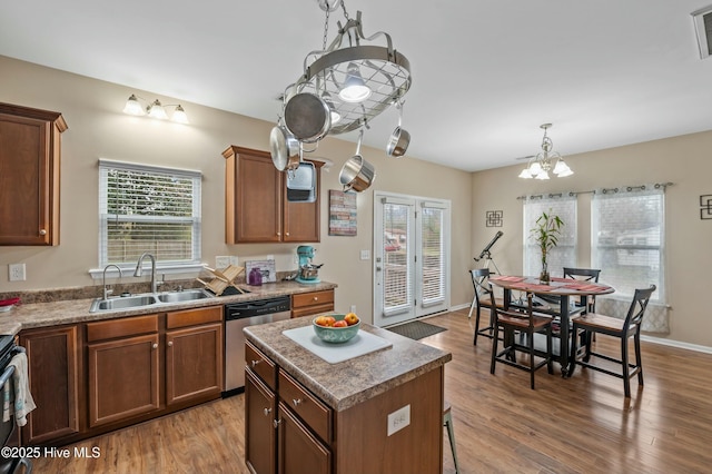 kitchen featuring a kitchen island, a sink, stainless steel dishwasher, and wood finished floors