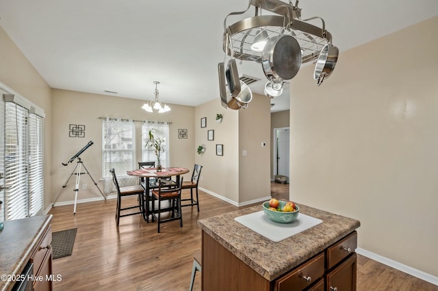 dining room with a chandelier, visible vents, baseboards, and wood finished floors