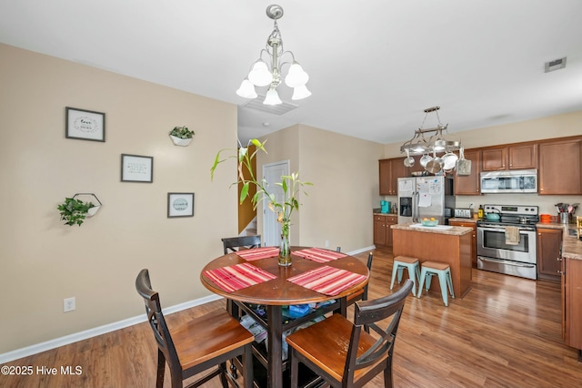 dining area featuring light wood-style floors, visible vents, baseboards, and an inviting chandelier