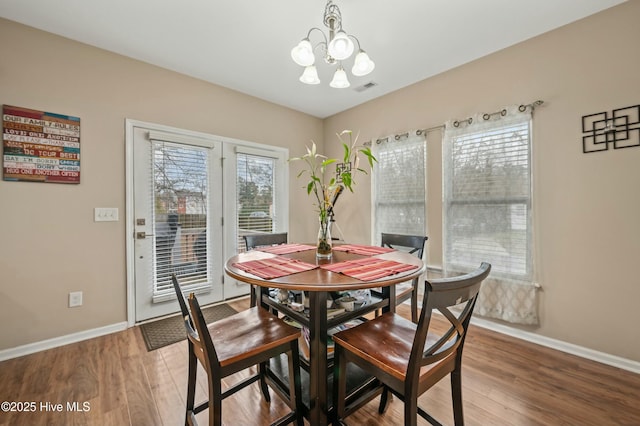 dining room with a chandelier, visible vents, baseboards, and wood finished floors