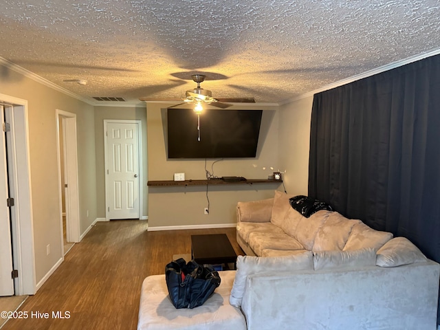 living area with a textured ceiling, visible vents, wood finished floors, and ornamental molding