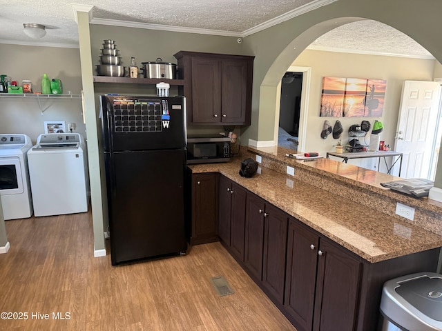 kitchen with light wood finished floors, stainless steel microwave, freestanding refrigerator, washing machine and dryer, and a textured ceiling