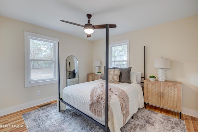 bedroom featuring a ceiling fan, wood finished floors, visible vents, and baseboards