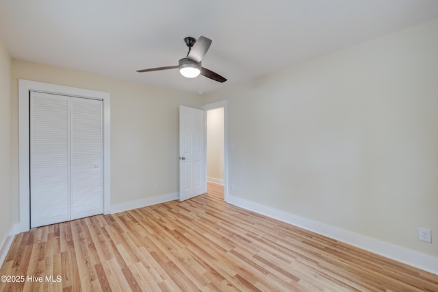 unfurnished bedroom featuring a ceiling fan, a closet, light wood-style flooring, and baseboards