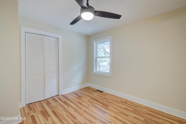 unfurnished bedroom featuring a closet, visible vents, light wood-style flooring, ceiling fan, and baseboards