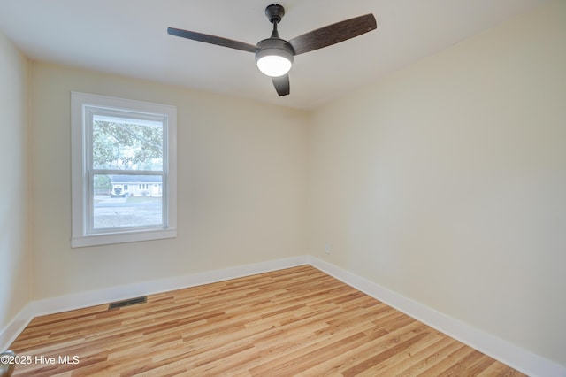 empty room featuring a ceiling fan, visible vents, baseboards, and wood finished floors