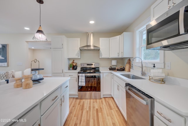 kitchen featuring wall chimney exhaust hood, appliances with stainless steel finishes, a sink, and white cabinets