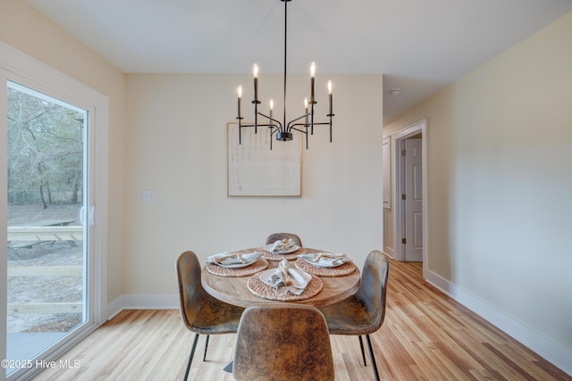 dining space with baseboards, a chandelier, and light wood-style floors