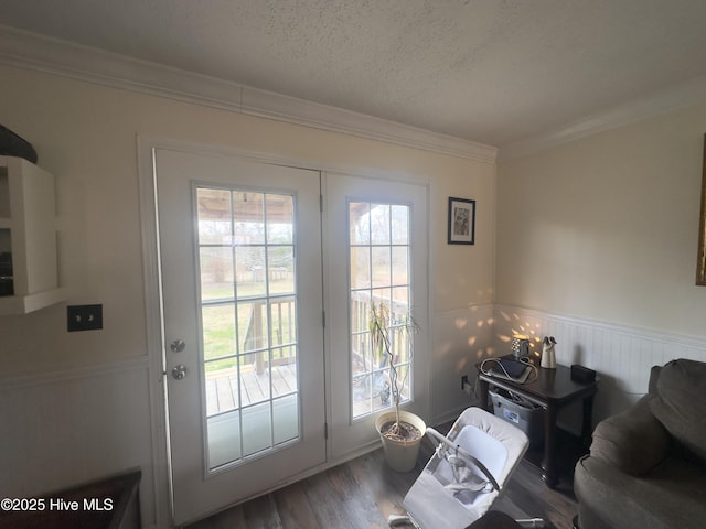 doorway to outside featuring a wealth of natural light, a wainscoted wall, wood finished floors, and ornamental molding