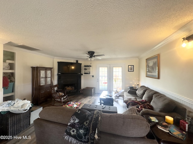 living area with visible vents, a wainscoted wall, ornamental molding, wood finished floors, and a fireplace