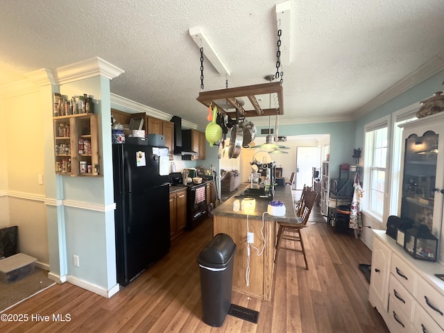 kitchen featuring black appliances, a kitchen breakfast bar, wood finished floors, crown molding, and wall chimney range hood