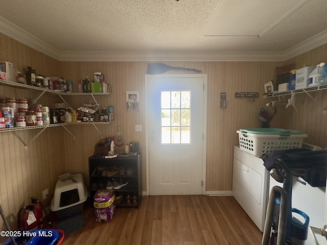 clothes washing area with laundry area, wood finished floors, baseboards, and ornamental molding