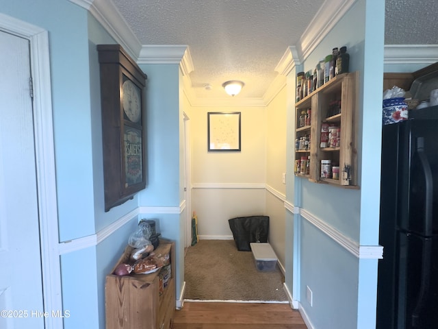 hallway with crown molding, wood finished floors, baseboards, and a textured ceiling