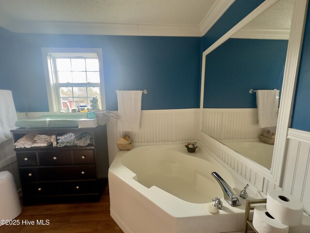 full bathroom featuring a bath, a wainscoted wall, ornamental molding, and wood finished floors