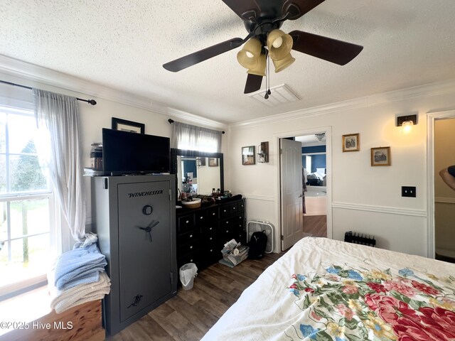 bedroom with ornamental molding, a textured ceiling, ceiling fan, and wood finished floors