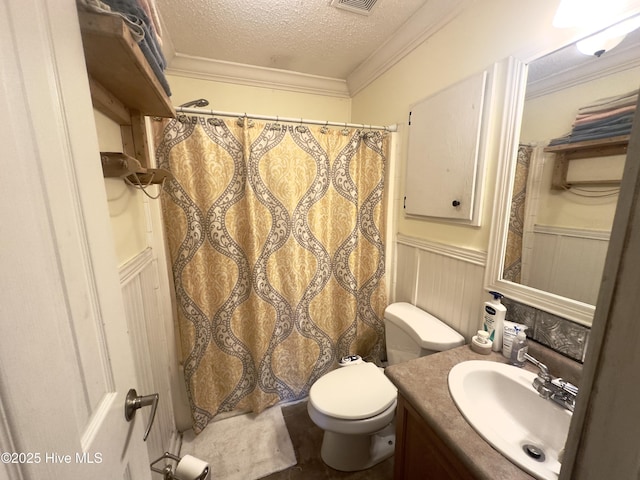 bathroom featuring a textured ceiling, toilet, wainscoting, and crown molding