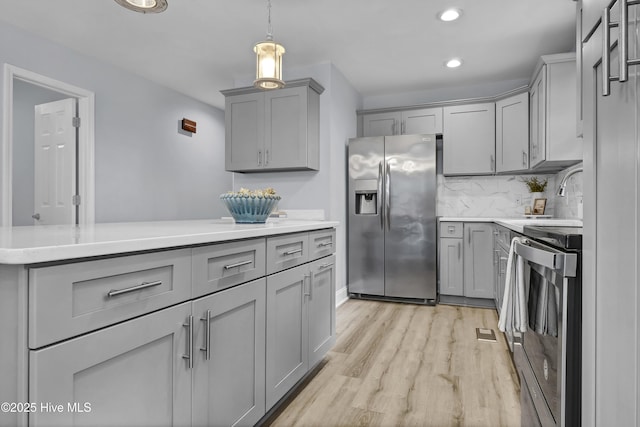 kitchen featuring light countertops, gray cabinets, stainless steel fridge, and stove