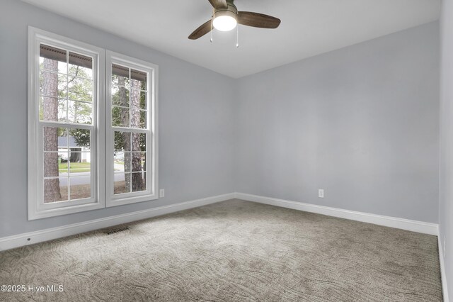 carpeted spare room with visible vents, ceiling fan, and baseboards