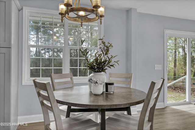 dining space featuring baseboards, wood finished floors, and a notable chandelier