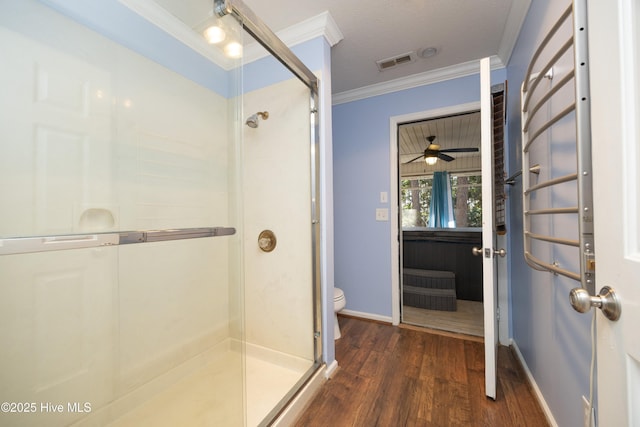 bathroom featuring visible vents, toilet, a stall shower, wood finished floors, and crown molding