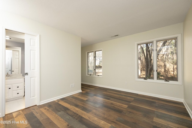 unfurnished bedroom featuring a sink, visible vents, baseboards, and dark wood-style flooring