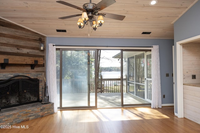 doorway featuring a water view, wood finished floors, a stone fireplace, wooden ceiling, and lofted ceiling