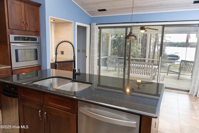 kitchen featuring a sink, stainless steel appliances, a wealth of natural light, and dark stone countertops