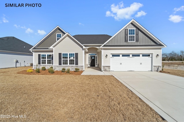 craftsman inspired home featuring stone siding, board and batten siding, concrete driveway, and a front lawn