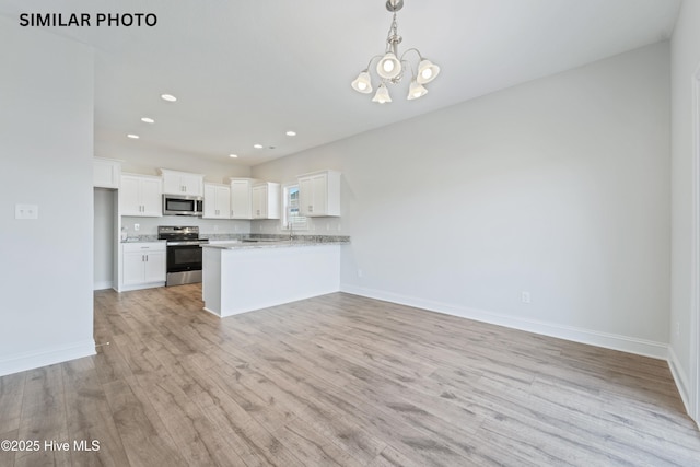 kitchen featuring baseboards, light wood-style flooring, appliances with stainless steel finishes, white cabinetry, and a notable chandelier