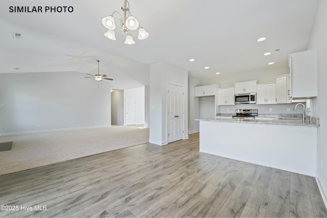 kitchen featuring light stone countertops, a sink, stainless steel appliances, white cabinets, and light wood-type flooring