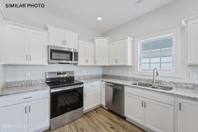 kitchen with a sink, stainless steel appliances, light wood-style floors, and white cabinets