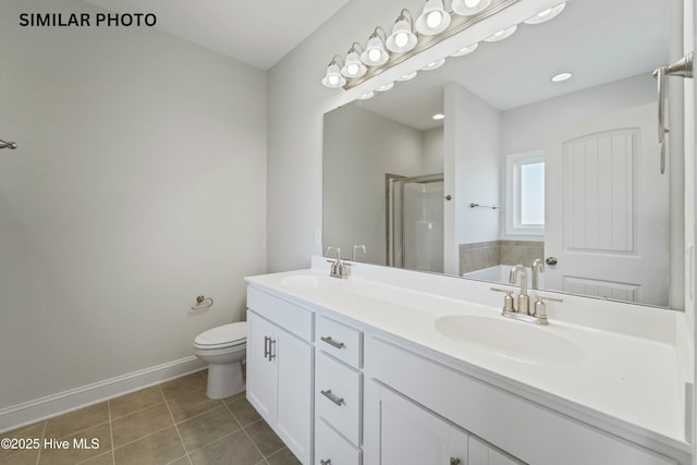 bathroom featuring tile patterned floors, a stall shower, double vanity, and a sink