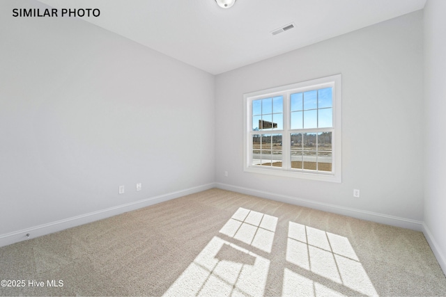 spare room featuring visible vents, baseboards, and light colored carpet