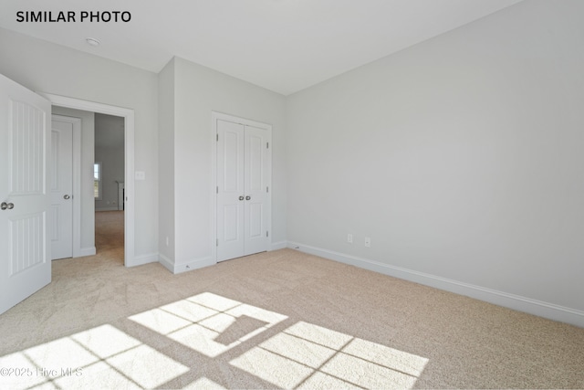 unfurnished bedroom featuring a closet, baseboards, and light colored carpet