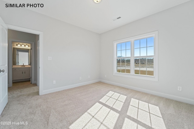 spare room with a sink, visible vents, light carpet, and baseboards