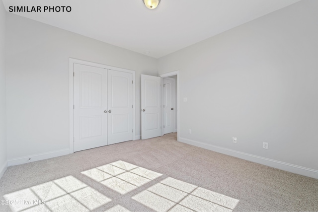 unfurnished bedroom featuring carpet flooring, baseboards, and a closet