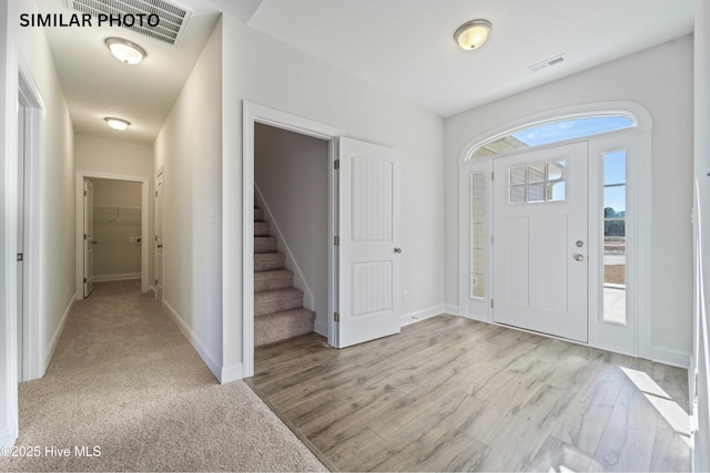 foyer featuring light wood finished floors, visible vents, stairway, and baseboards