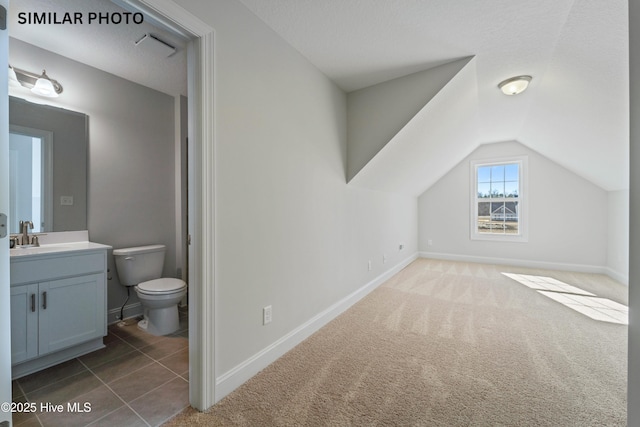 bathroom featuring toilet, lofted ceiling, a textured ceiling, baseboards, and vanity