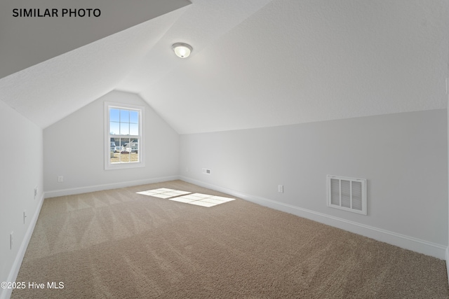 bonus room featuring lofted ceiling, baseboards, visible vents, and light carpet