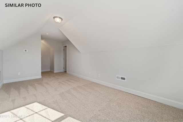 bonus room with visible vents, light colored carpet, lofted ceiling, and baseboards