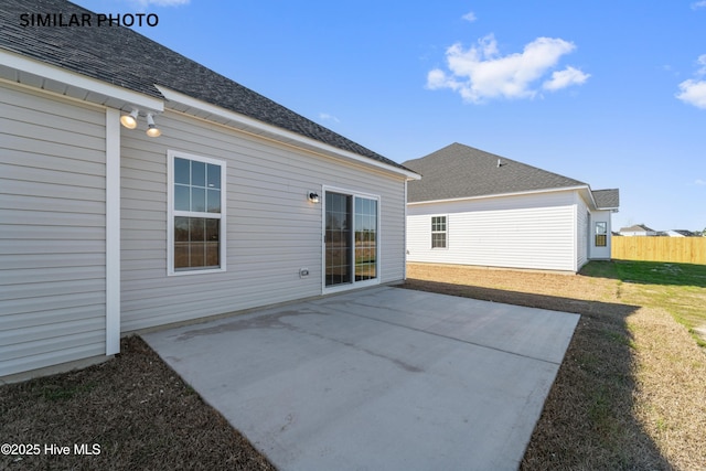 rear view of house with a yard, a patio area, fence, and roof with shingles